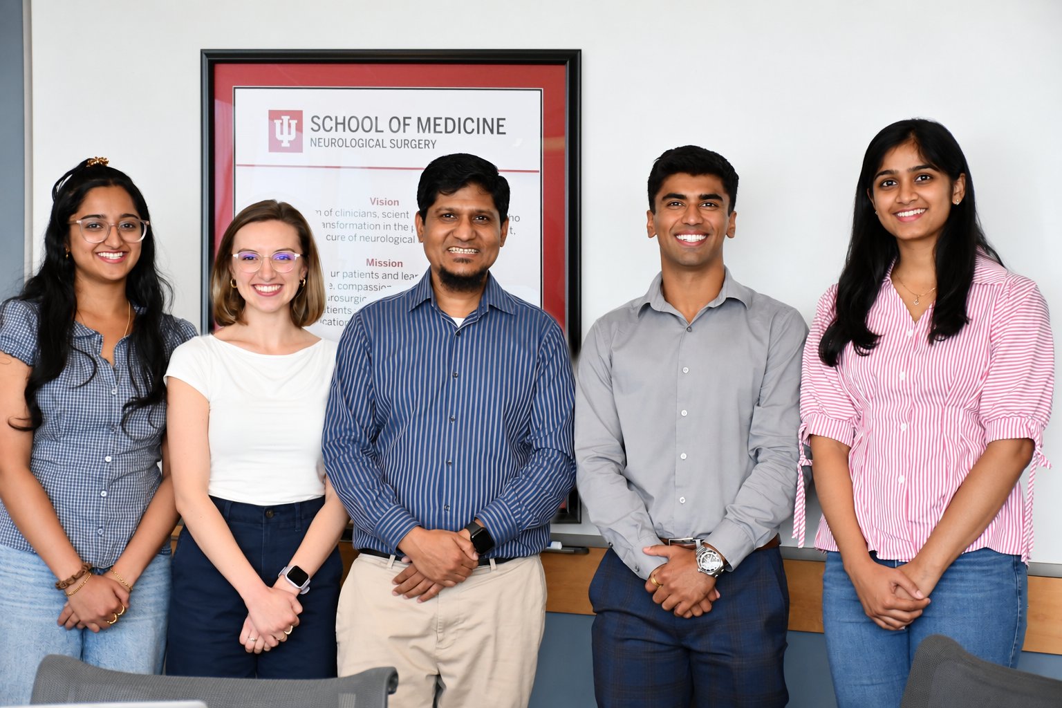Dr. Noor and NPN Lab members standing together in front of the Indiana University School of Medicine Neurological Surgery sign